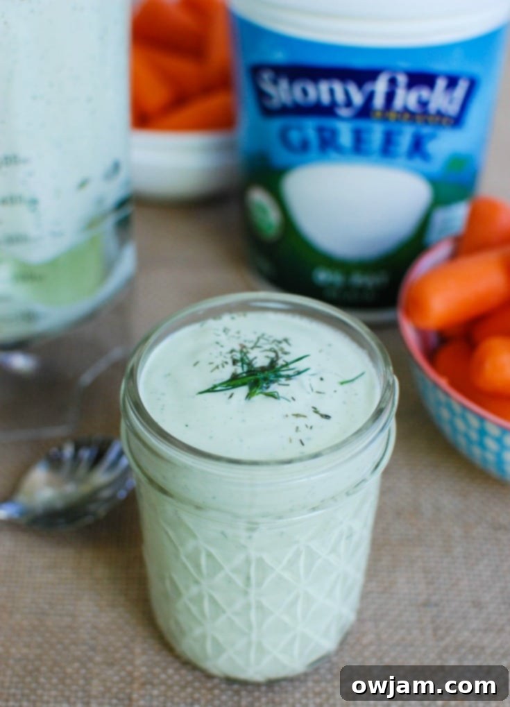 A spoon scooping creamy dill sauce from a mason jar, showcasing its rich, smooth texture and fresh green flecks of dill.