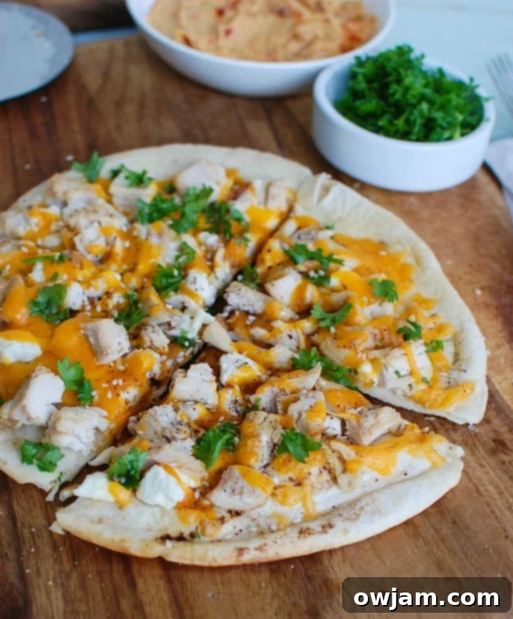 Chicken Feta Cheddar Pita Pizzazz 2 Chicken Feta Cheddar Pita Pitza on a cutting board, garnished with fresh parsley.