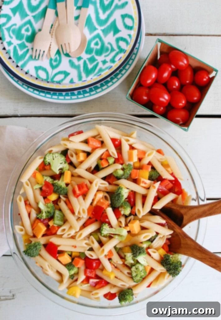 A large bowl of vibrant Classic Pasta Salad, bursting with fresh vegetables and cheese, ready for a summer picnic.
