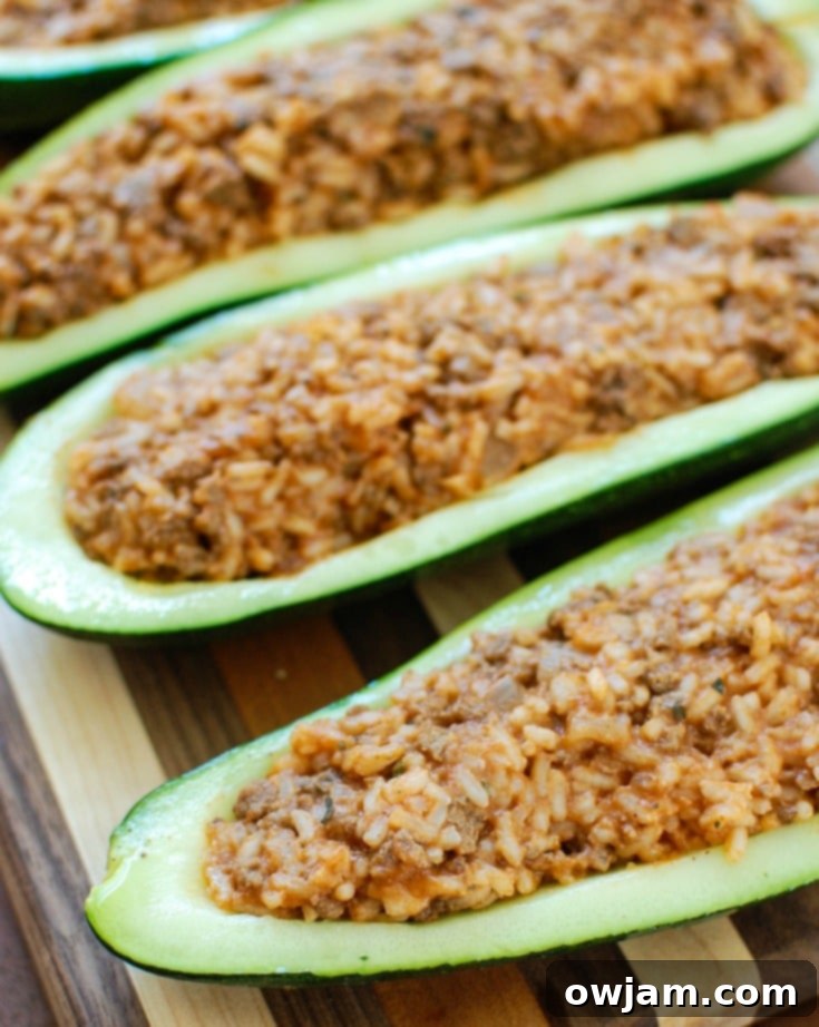 Vibrant Mediterranean Zucchini Boats 5 Two Mediterranean Zucchini Boats on a baking sheet, topped with shredded mozzarella cheese, ready to be returned to the oven for melting.