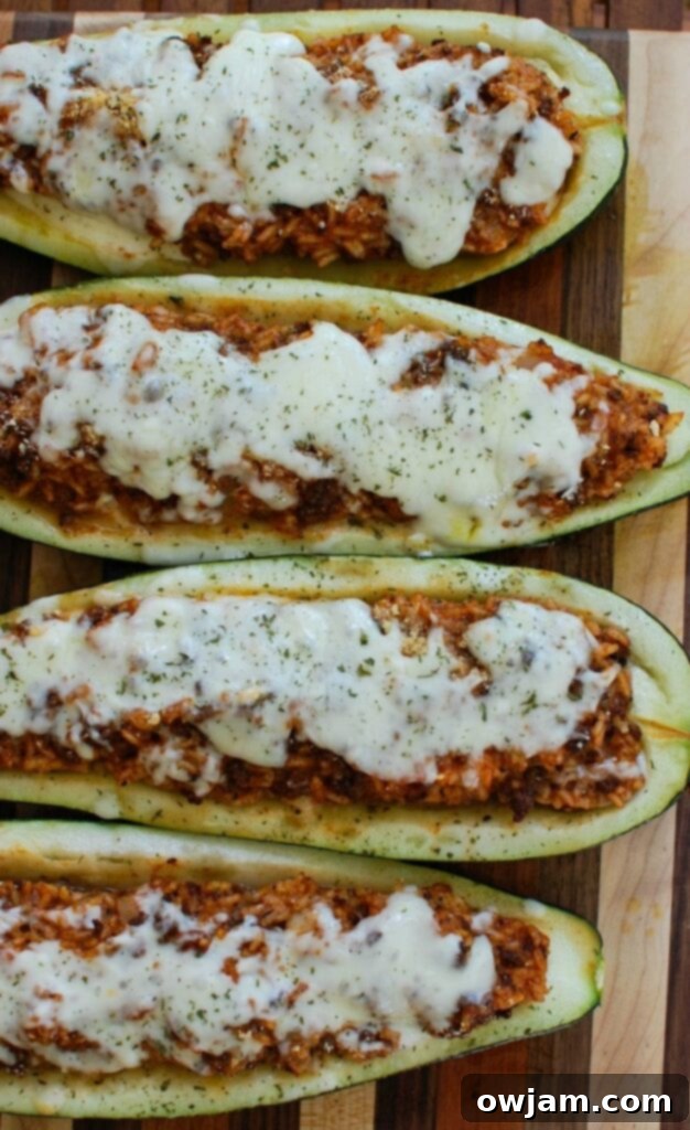 Vibrant Mediterranean Zucchini Boats 6 A close-up of a single Mediterranean Zucchini Boat, stuffed with a rich meat and rice filling, topped with melted cheese and fresh parsley, ready to be enjoyed.
