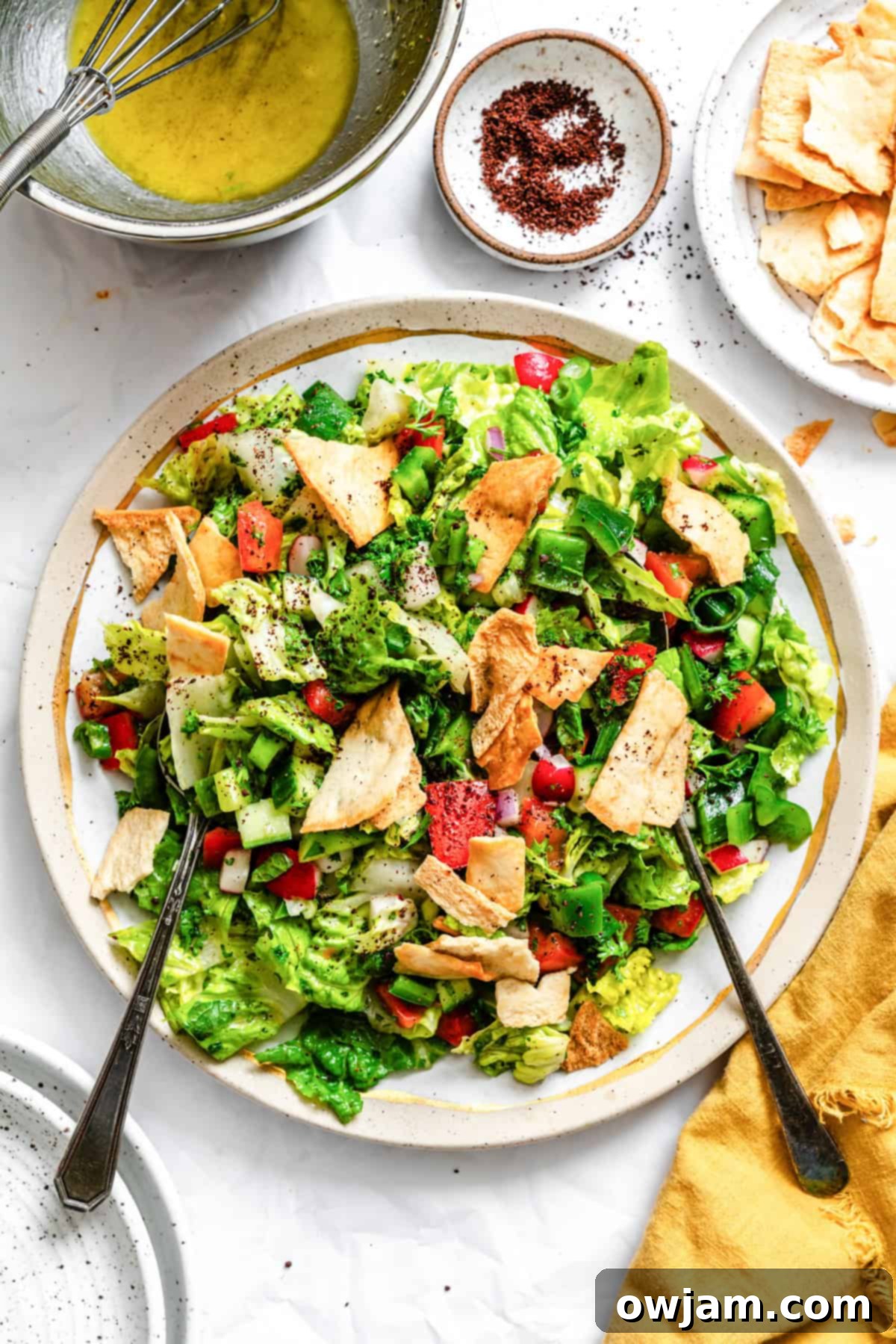A bowl of Fattoush Salad served with two wooden spoons, ready to be enjoyed