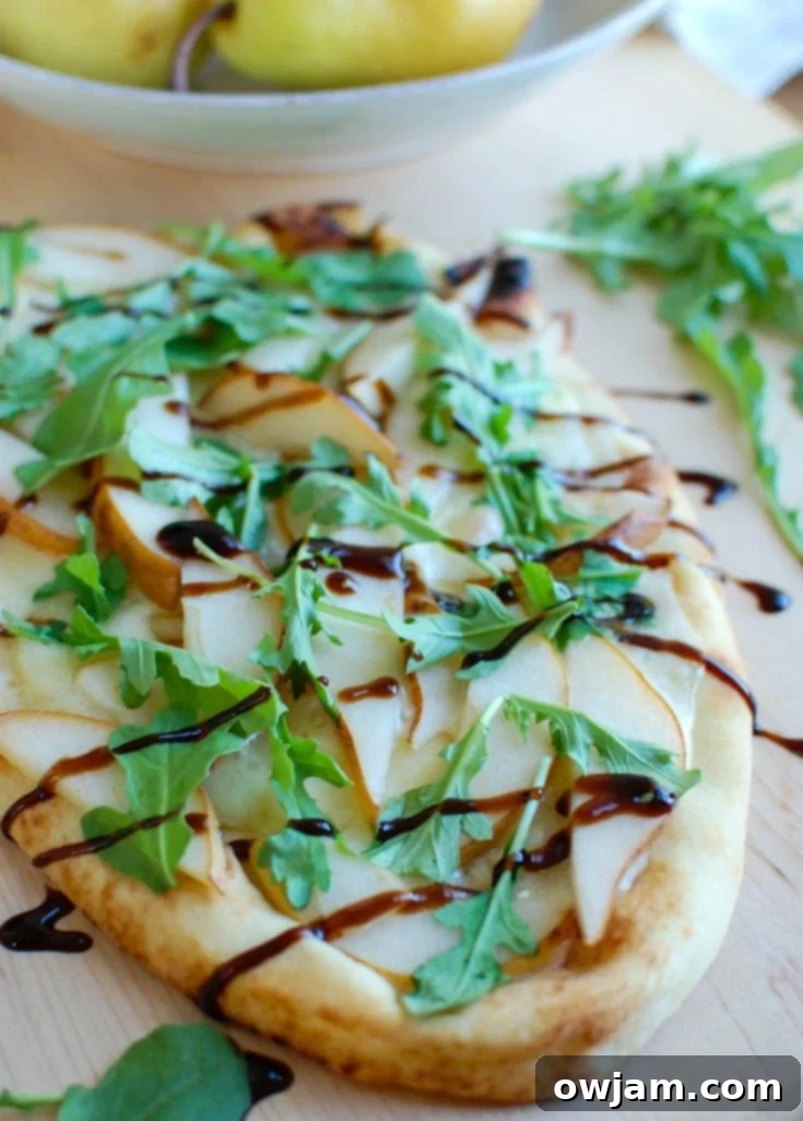 Warm Pear Brie Arugula Naan is the perfect holiday appetizer that will impress your guests. This beautiful flatbread is warmed in the oven with brie cheese and pear and then topped with arugula and a drizzle of balsamic glaze.