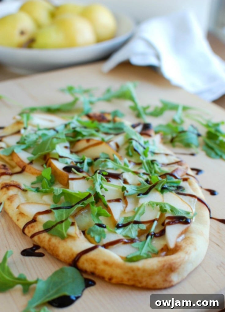 Warm Pear Brie Arugula Naan garnished with fresh arugula. A simple and elegant appetizer.
