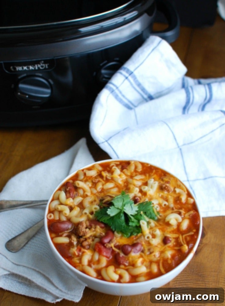 A bowl of Crock-Pot Turkey Chili Mac and Cheese with a spoon, ready to eat.