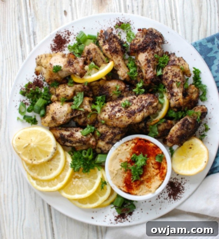Zesty Sumac Lemon Baked Chicken Wings 4 Sumac Lemon Baked Chicken Wings on a baking sheet, fresh out of the oven, garnished with herbs.