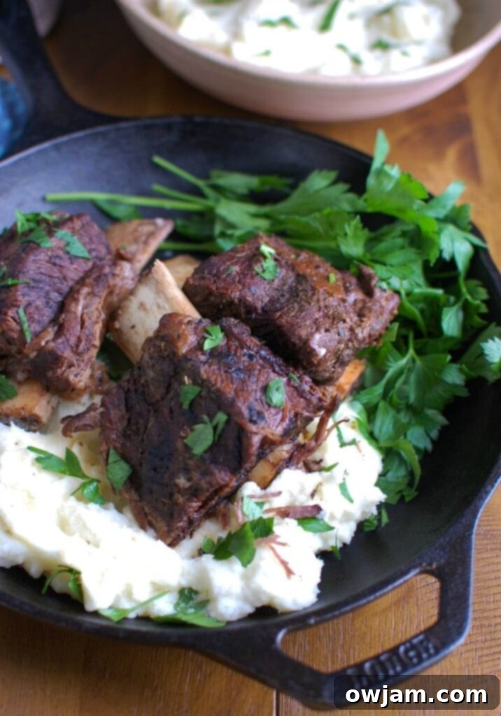 Effortlessly Elegant Red Wine Slow Cooker Ribs 2 Close-up of tender Slow Cooker Red Wine Short Ribs served with mashed potatoes, garnished with fresh parsley.