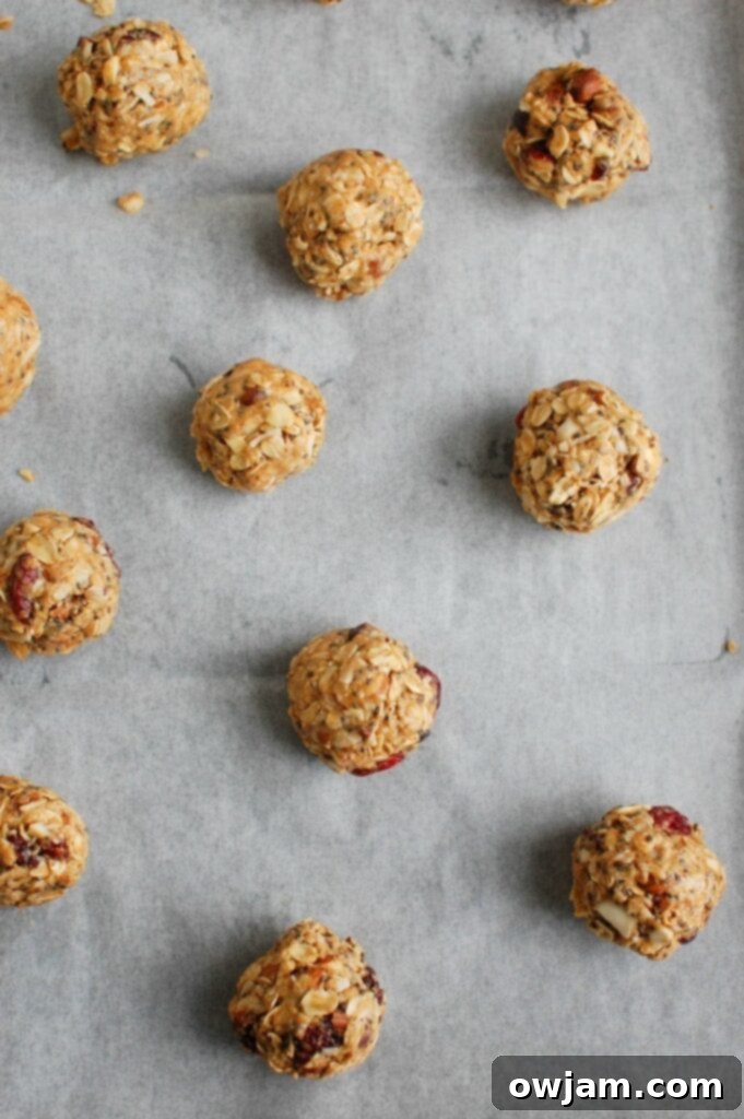 Almond Cranberry Recharge Bites 5 Hands carefully rolling the Cranberry Almond Energy Bites mixture into perfectly uniform, bite-sized balls, which are then placed on a baking sheet thoughtfully lined with wax paper to prevent sticking and prepare for chilling.