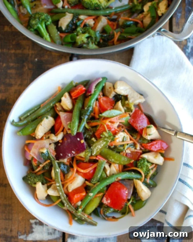 A vibrant bowl of homemade Orange Chicken Vegetable Stir Fry, featuring perfectly cooked chicken, crisp broccoli, colorful bell peppers, and fresh snow peas, all coated in a light orange sauce and garnished with fresh herbs.