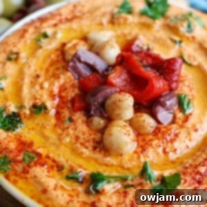 Creamy Roasted Red Pepper and Greek Yogurt Hummus 6 Roasted Red Pepper Greek Yogurt Hummus served in a bowl, with a side of pita bread.