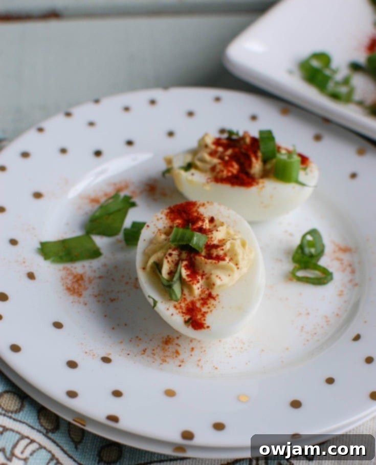 A close-up of a single Southwestern Greek Yogurt Deviled Egg, showcasing the creamy filling piped into the egg white, with fresh cilantro and paprika garnish.