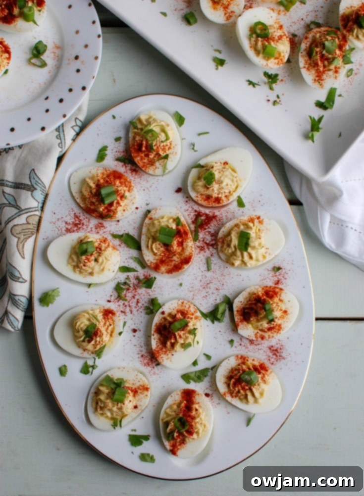 An overhead shot of a platter of Southwestern Greek Yogurt Deviled Eggs, artfully arranged and garnished, with extra paprika sprinkled for color.