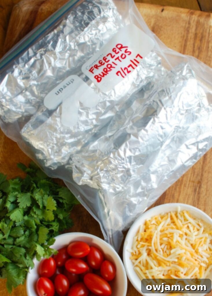 Several Vegetarian Breakfast Egg Burritos individually wrapped in foil, ready for freezing.