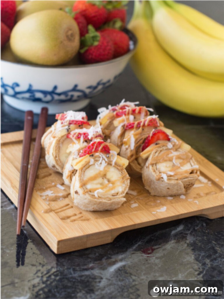 Sweet Banana Sushi Rolls 2 Close-up of freshly made banana sushi rolls with strawberry and kiwi slices on top.