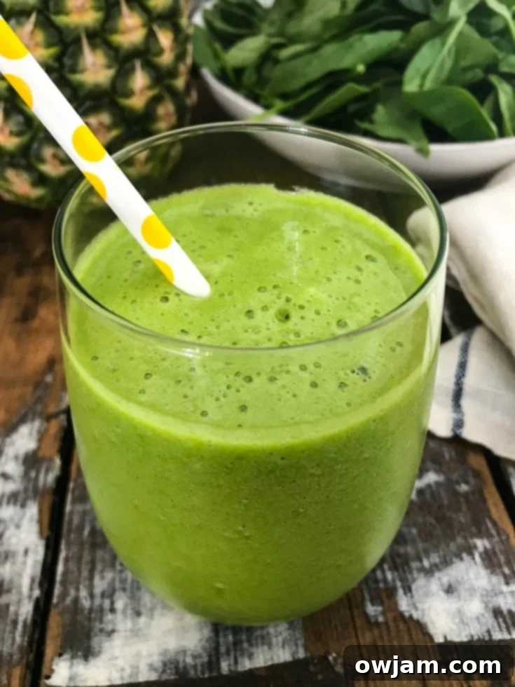 Close-up of a Tropical Green Smoothie in a glass, showcasing its smooth texture and vibrant green color.