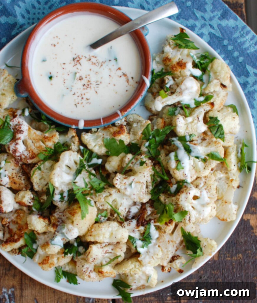 Zaatar Roasted Cauliflower with Creamy Tahini 2 Golden brown Za'atar Roasted Cauliflower florets generously drizzled with creamy Yogurt Tahini Sauce and fresh parsley, served on a rustic plate.