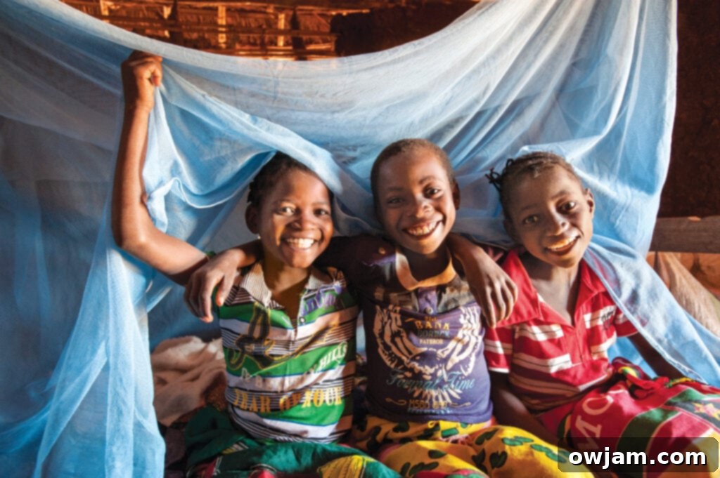 Delfina and friends smiling with a new mosquito net, a gift from World Vision, representing health and protection.