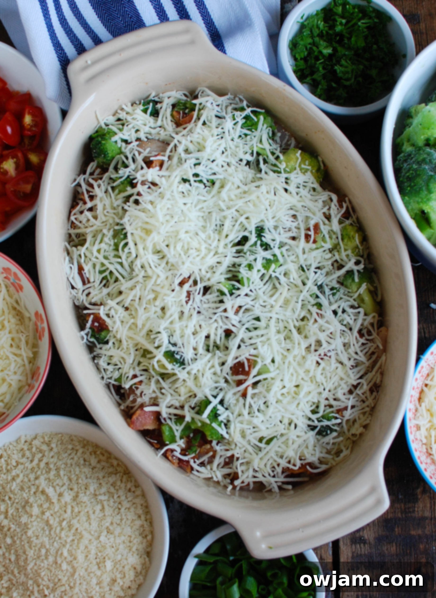 Cheesy Chicken and Broccoli Bake 6 A casserole dish showing chicken, broccoli, and bacon generously covered with Sargento® Shredded 6 Cheese Italian, Monterey Jack Cheese, and panko breadcrumbs, before baking.