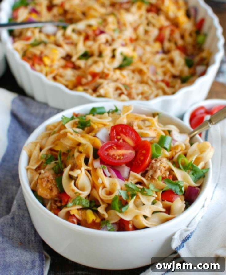 A vibrant Easy Mexican Noodle Casserole baked to perfection, garnished with fresh cilantro, diced tomatoes, and red onions, showcasing the colorful ingredients and golden-brown cheese. Perfect for a family meal.