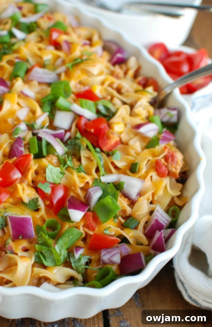 Close-up of Easy Mexican Noodle Casserole, showing the rich, cheesy top layer and the tender No Yolks Noodles mixed with ground turkey, corn, and diced tomatoes. A perfect blend of Mexican flavors and comfort food.