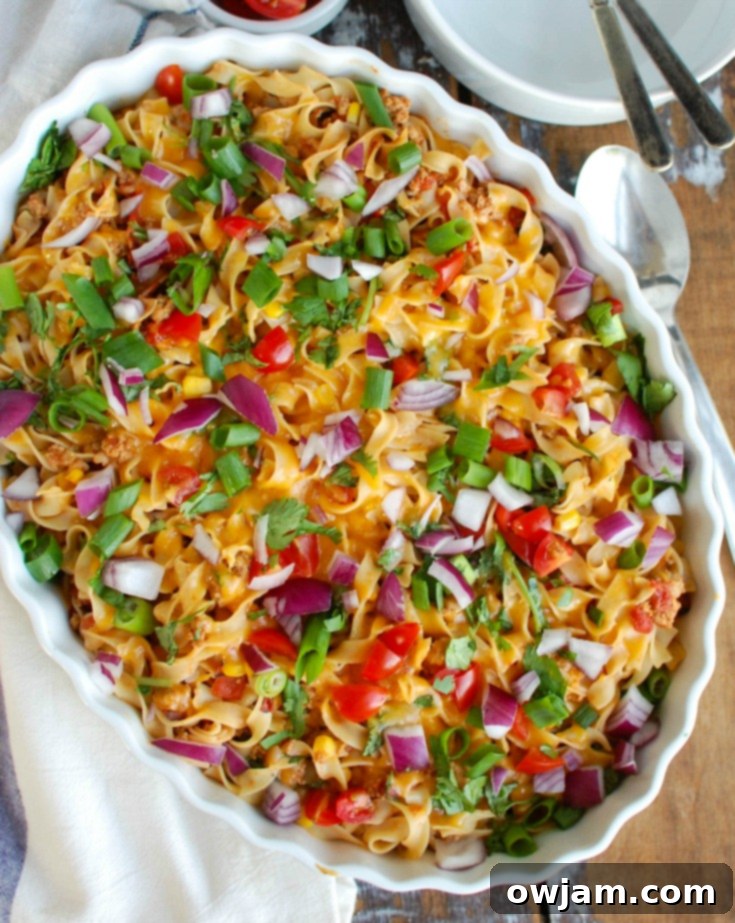 A serving of Easy Mexican Noodle Casserole on a plate, topped with fresh garnishes like avocado, red onion, and cilantro, ready to be enjoyed.