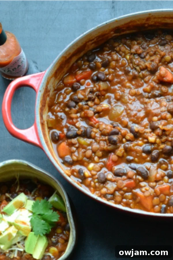 Hearty black bean and lentil chili, garnished with fresh cilantro and a lime wedge.