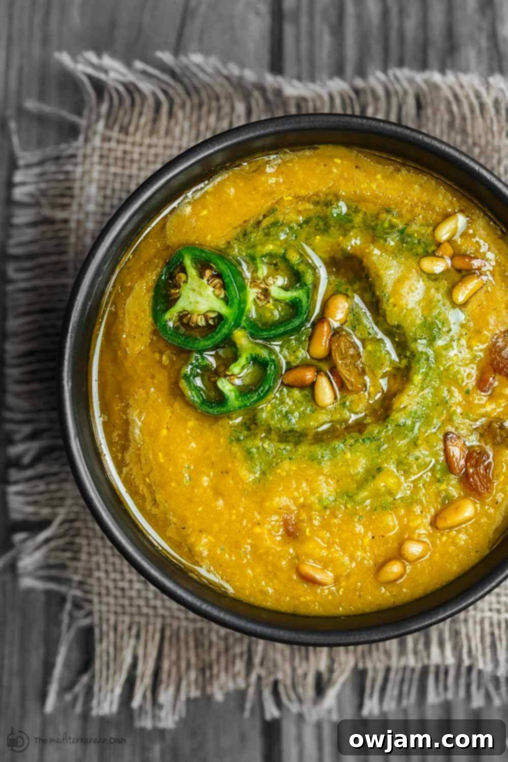 Creamy and comforting lentil pumpkin soup garnished with fresh herbs.