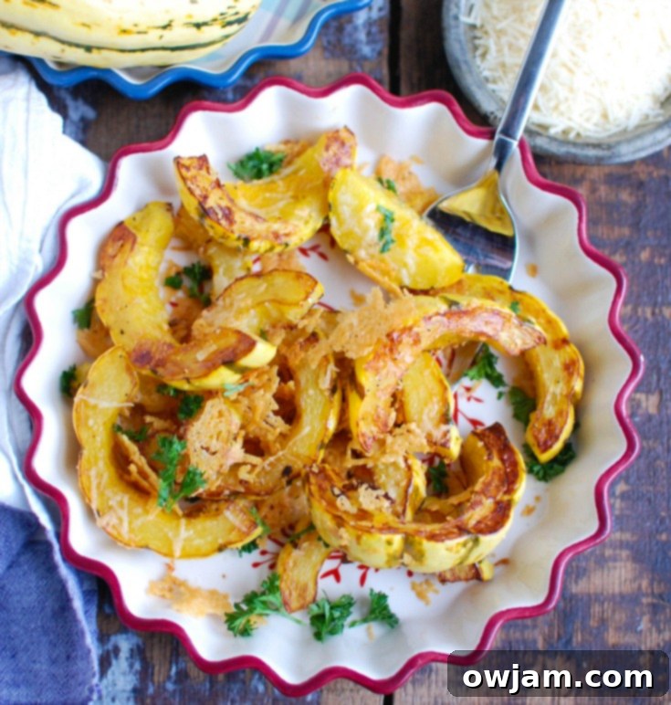 Close-up of golden-brown roasted delicata squash slices with melted Parmesan cheese, garnished with fresh green parsley.