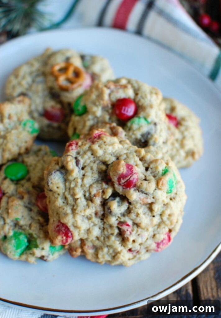 A stack of golden brown Peanut Butter Pretzel Chocolate Chip Cookies on a plate, highlighting the delicious mix of textures and colors from the M&Ms, pretzels, and chocolate chips.