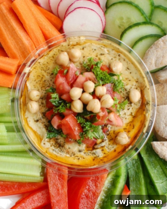 Creamy hummus is topped with diced tomatoes, fresh parsley and mint, chickpeas, pine nuts and a squeeze of lemon juice. Serve this with a rainbow of vegetables and whole wheat pita.
