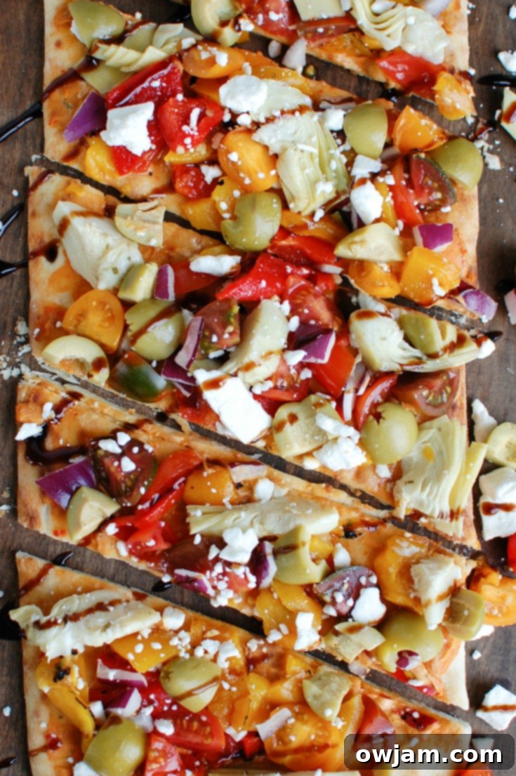 Rustic Mediterranean Flatbread 6 Beautifully garnished Mediterranean Flatbread on a baking sheet, ready to be enjoyed as a quick and healthy vegetarian meal.