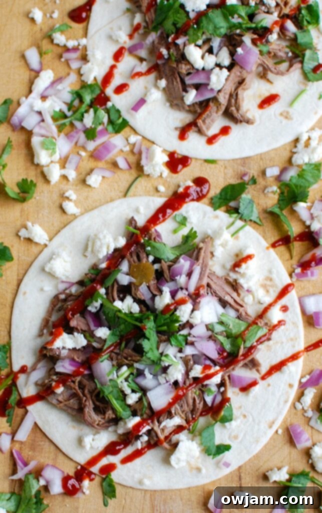 Cooked, tender Slow Cooker Beef Barbacoa ready for shredding, surrounded by rich sauce.