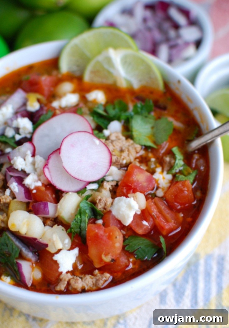 Close-up of Slow Cooker Pork Pozole in a bowl, topped with sliced radishes and cilantro.