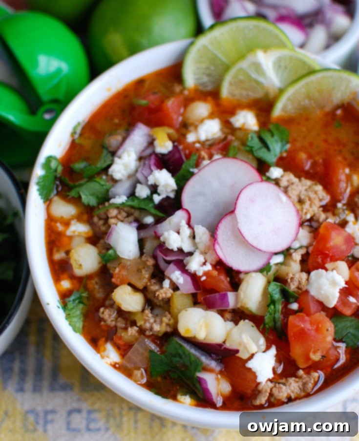 A bowl of Slow Cooker Pork Pozole with fresh lime wedges for garnish.