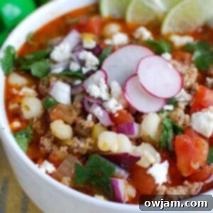 Slow Cooker Pork Pozole in a white bowl, garnished.
