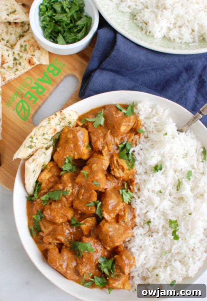 Slow Cooker Butter Chicken served in a bowl with rice and naan