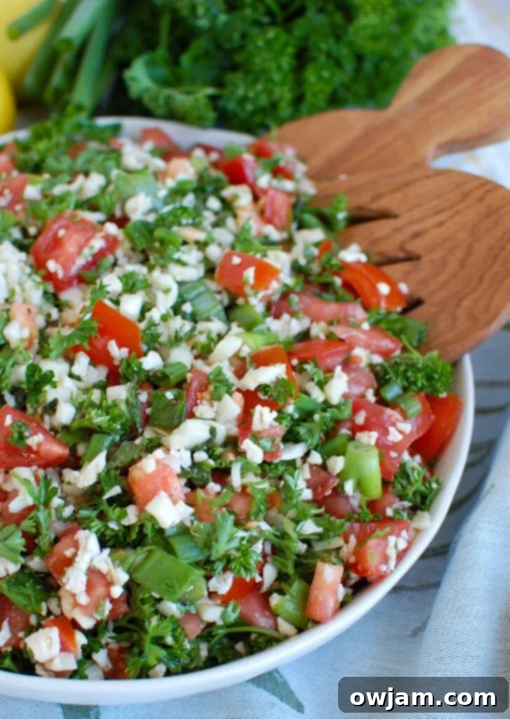 Cauliflower Tabbouleh in a bowl with a wooden spoon, ready to be tossed