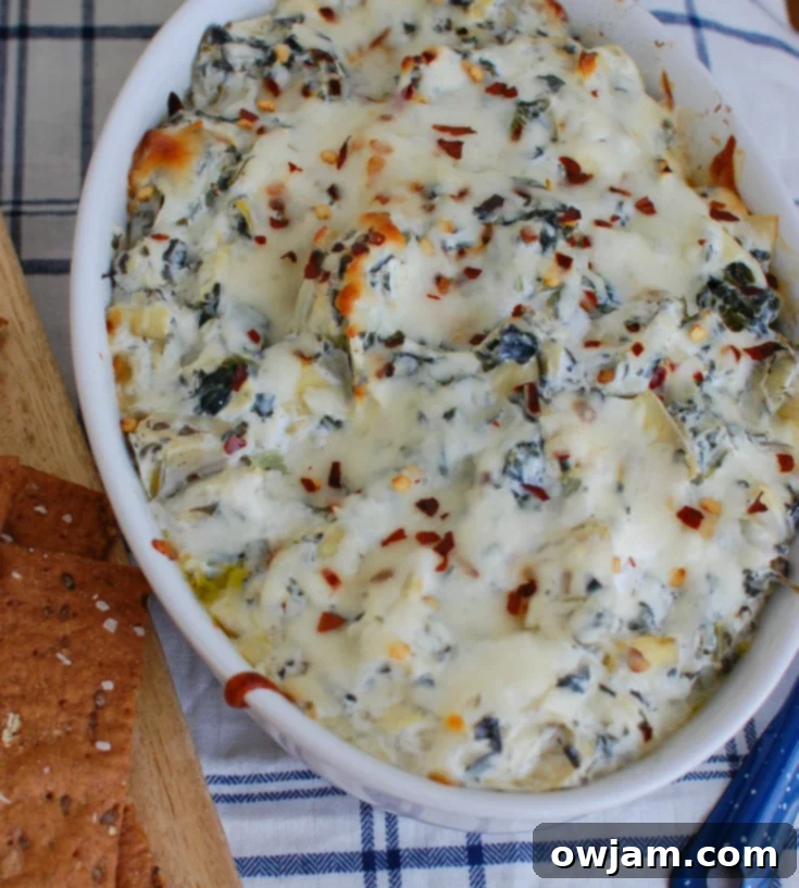 Zesty Lemon Spinach Artichoke Dip 5 Lemon Spinach Artichoke Dip served in a white bowl with dippers