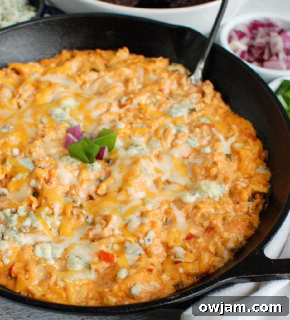 Hearty Buffalo Chicken Queso Cheese Dip served in a black cast iron skillet, with dippers around, showcasing its appealing texture