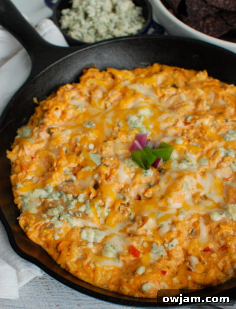 A side view of the Buffalo Queso Cheese Chicken Dip in a baking dish, showing its appealing golden-brown top and melted cheese