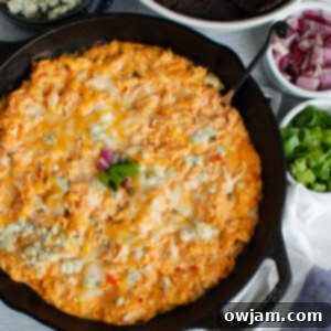 Buffalo Chicken Queso Cheese Dip in a skillet, top down view, garnished
