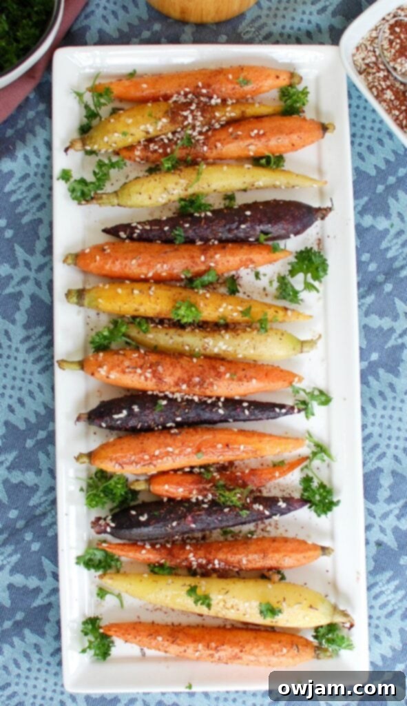 Several neatly arranged Za'atar Roasted Carrots laid out in a row on a baking sheet, ready for serving.