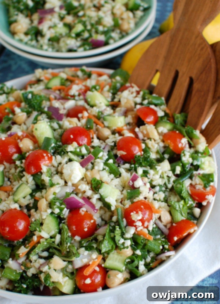 Mediterranean Chickpea Cauliflower Salad with serving tongs in a rustic bowl.