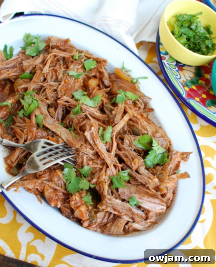 Slow Cooker Mexican Beef Brisket on a white plate with tortillas and lime wedges