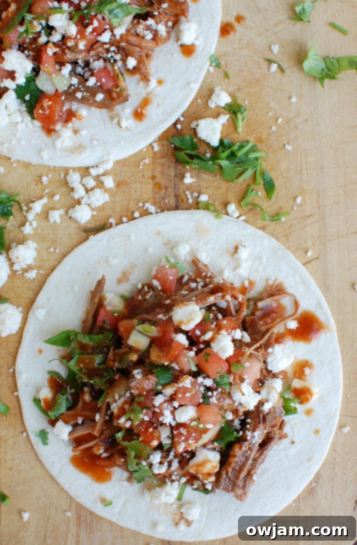 Two Slow Cooker Mexican Beef Brisket tacos on a wooden board