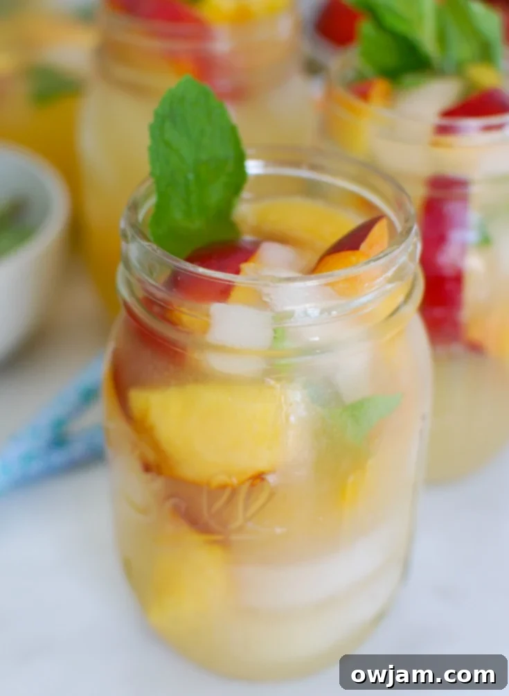 Zesty Peach Sparkle 2 Sparkling Peach Lemonade served in a Mason Jar with fresh mint and peach slices, perfect for summer.