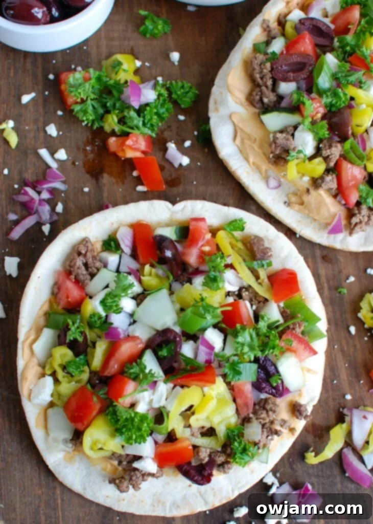 Overhead shot of two Greek Beef Pita Pizzas, showcasing all the fresh and vibrant toppings.