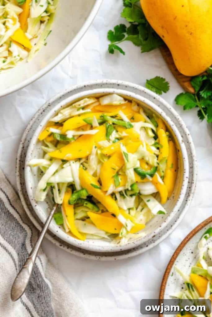 Quick Tropical Mango Cabbage Slaw 5 Easy Mango Cabbage Coleslaw in a white bowl with a fork, showing its vibrant colors