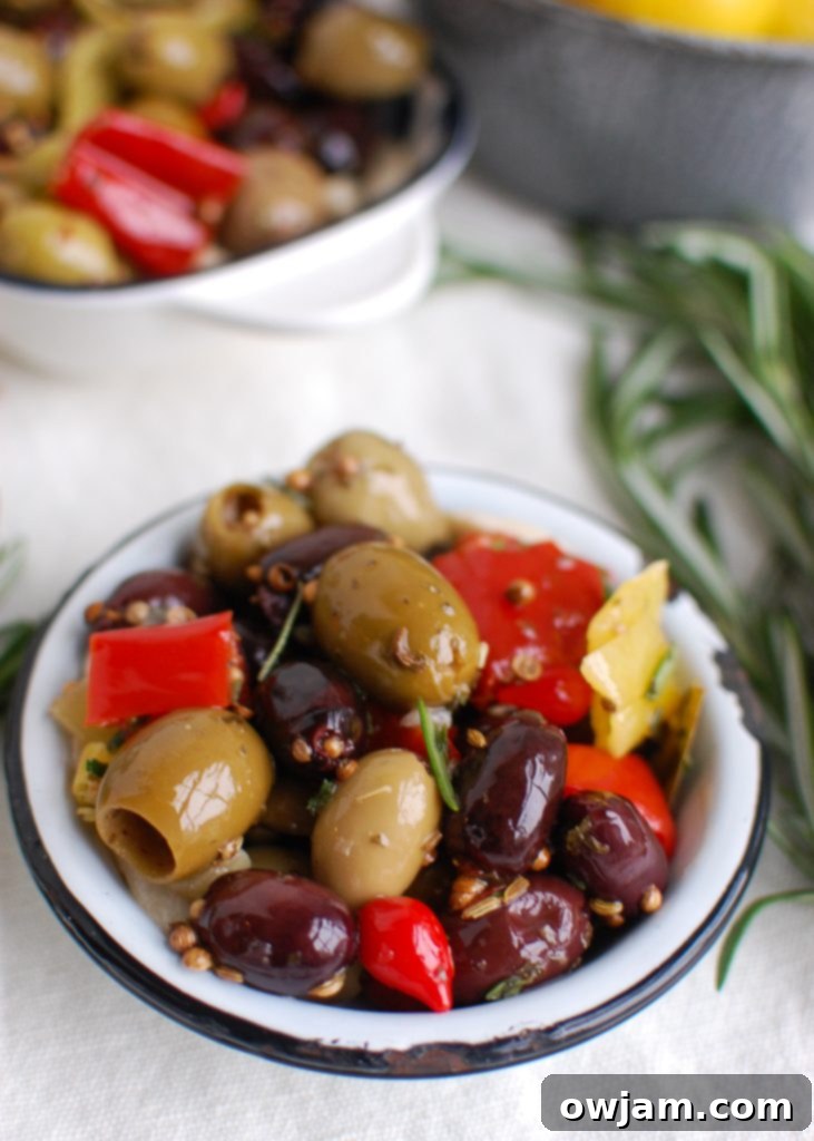Lemon Marinated Olives in a pristine white bowl, garnished with fresh rosemary and lemon slices
