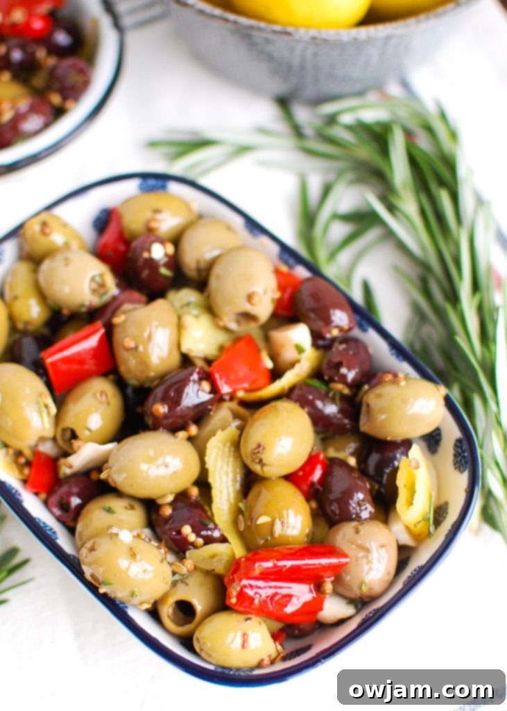 Lemon Marinated Olives in a small, elegant blue dish, garnished with fresh rosemary sprigs